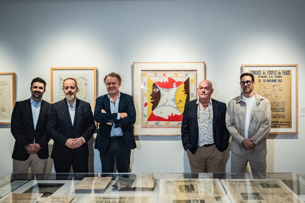 Interior de una sala expositiva con obras enmarcadas y vitrinas sobre un suelo brillante