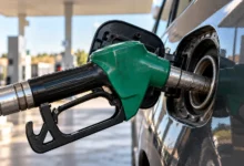 Primer plano del boquerel de un surtidor de gasolina introducido en la boca de llenado de un vehículo, con detalles metálicos y de goma.