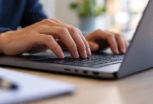 Primer plano de un teclado de ordenador y una pantalla desenfocada que representan la tramitación electrónica municipal.