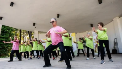 Grupo de personas mayores realizando ejercicios físicos sobre un escenario cubierto