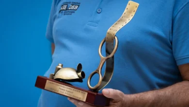 Persona sin rostro visible con polo azul de ASEDEB sostiene un trofeo del Espeleo Canyoning Cinema ASEDEB 2026