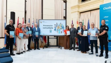 Grupo de personas junto a una pantalla con el título Prevención comunitaria durante una presentación en Málaga